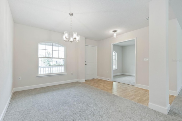 unfurnished room featuring a chandelier and carpet flooring