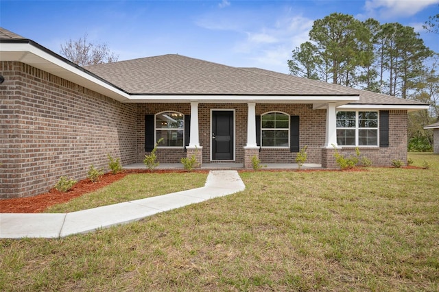 view of front of home with brick siding, a porch, a front lawn, and roof with shingles