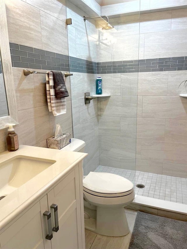 bathroom featuring toilet, vanity, tile walls, tiled shower, and decorative backsplash