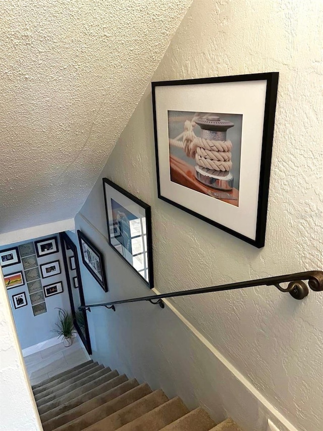 stairs with a textured ceiling and a textured wall