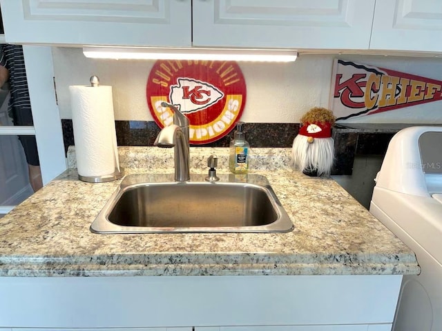 details with washer / clothes dryer, a sink, and white cabinetry