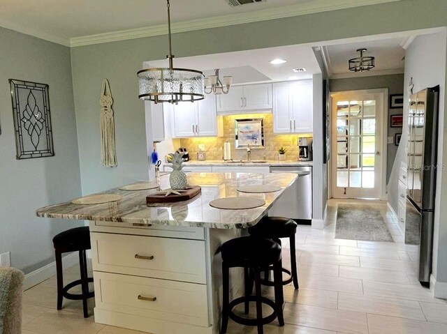 kitchen featuring tasteful backsplash, light stone counters, a breakfast bar area, stainless steel appliances, and crown molding