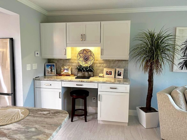 kitchen featuring freestanding refrigerator, white cabinetry, crown molding, and decorative backsplash