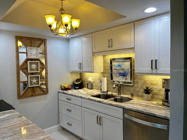 kitchen with stainless steel dishwasher, decorative backsplash, a sink, and light stone countertops