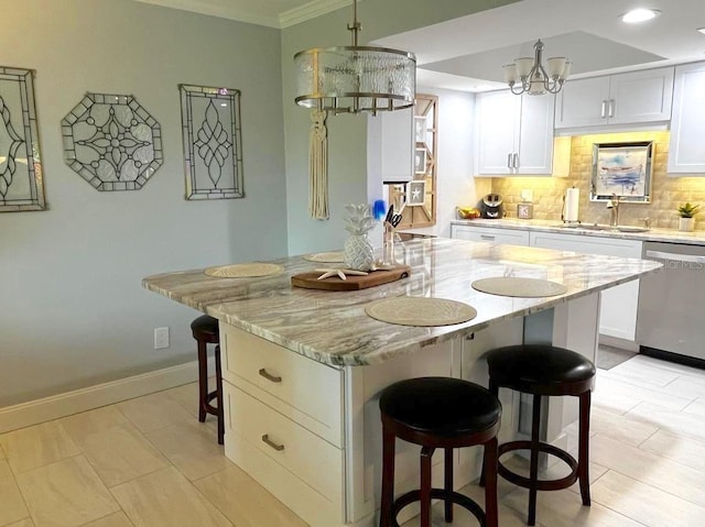 kitchen featuring a breakfast bar area, a sink, backsplash, dishwasher, and an inviting chandelier