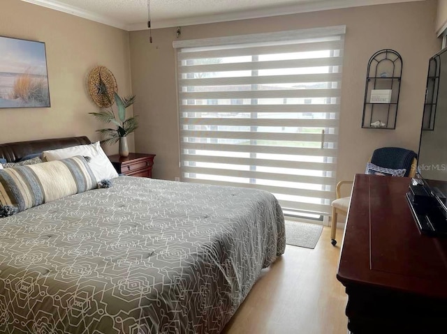 bedroom with ornamental molding, multiple windows, and wood finished floors