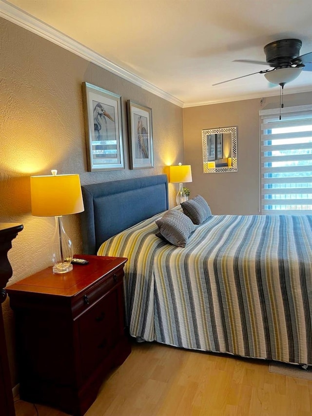 bedroom with a textured wall, ornamental molding, wood finished floors, and a ceiling fan