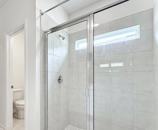 bathroom featuring toilet, an enclosed shower, and a healthy amount of sunlight