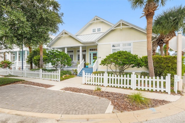 view of front of property with metal roof, a porch, a standing seam roof, and a fenced front yard