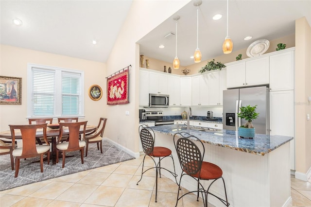 kitchen featuring white cabinetry, stainless steel appliances, a breakfast bar area, and light tile patterned flooring