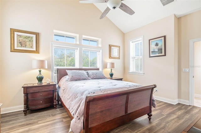 bedroom with vaulted ceiling, wood finished floors, visible vents, and baseboards