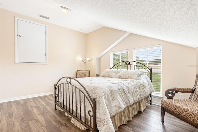 bedroom with baseboards, visible vents, vaulted ceiling, a textured ceiling, and light wood-style floors