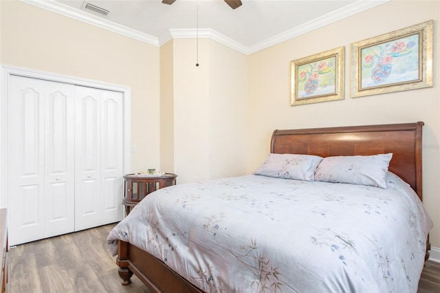 bedroom featuring ceiling fan, wood finished floors, visible vents, a closet, and crown molding