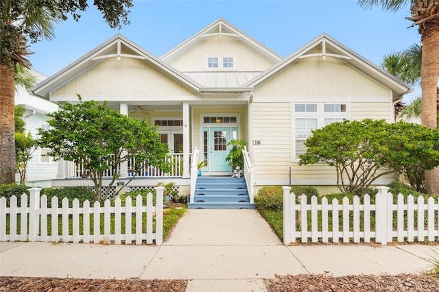 view of front of property with a fenced front yard, ceiling fan, metal roof, a standing seam roof, and a porch