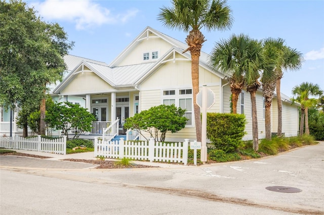 view of front of home featuring metal roof, a porch, a fenced front yard, french doors, and a standing seam roof