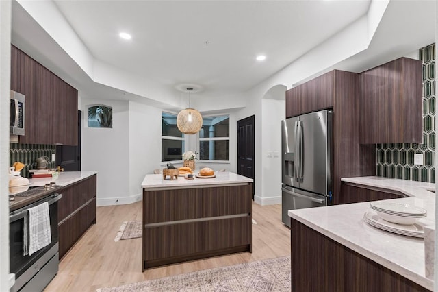 kitchen featuring a center island, appliances with stainless steel finishes, decorative backsplash, light hardwood / wood-style floors, and pendant lighting