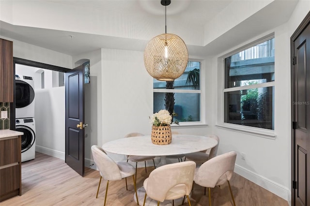 dining space with light wood-style floors, baseboards, and stacked washer and clothes dryer