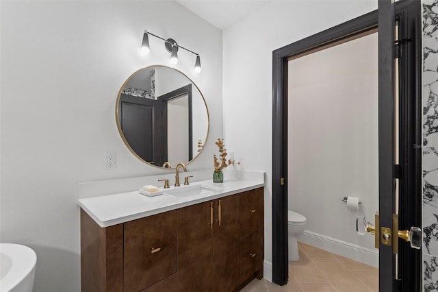 bathroom featuring toilet, tile patterned flooring, baseboards, and vanity