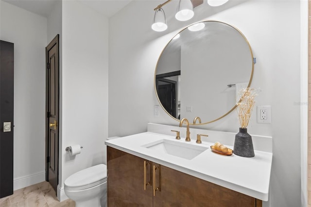 bathroom featuring marble finish floor, baseboards, vanity, and toilet