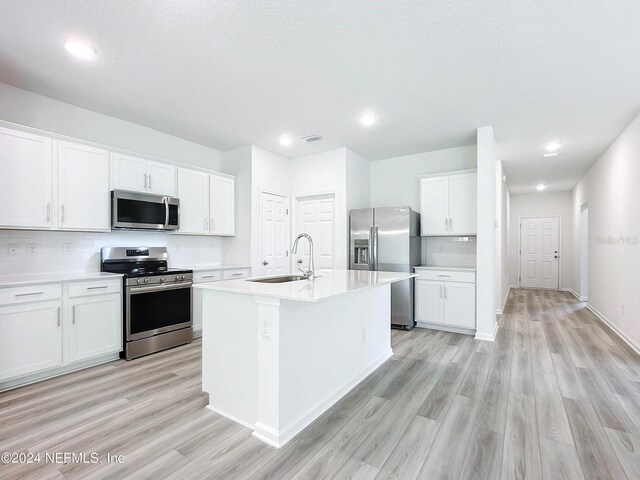 kitchen featuring light hardwood / wood-style flooring, white cabinetry, sink, a center island with sink, and stainless steel appliances