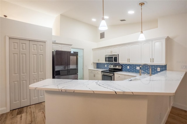 kitchen featuring white cabinetry, stainless steel appliances, decorative light fixtures, kitchen peninsula, and light hardwood / wood-style floors