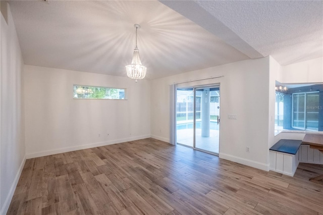 unfurnished room with light wood-type flooring, a healthy amount of sunlight, and a chandelier