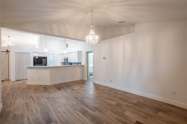 unfurnished living room featuring lofted ceiling, an inviting chandelier, and light hardwood / wood-style floors