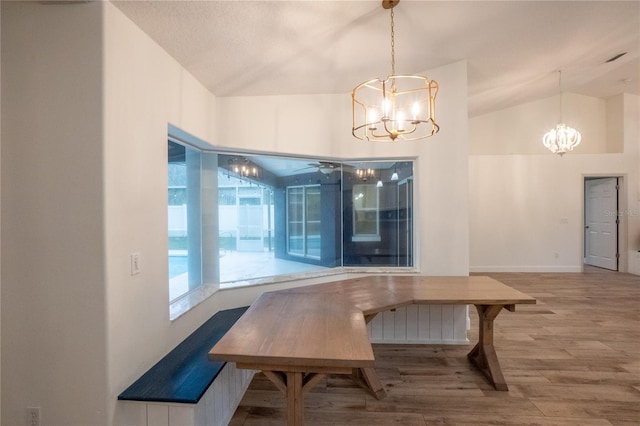 dining space with vaulted ceiling, a notable chandelier, and hardwood / wood-style flooring