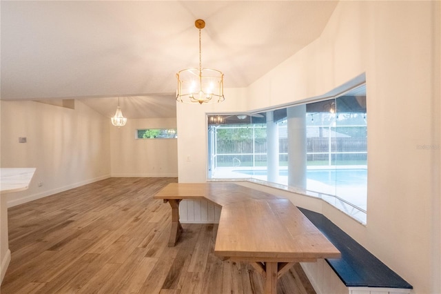 dining room with lofted ceiling, hardwood / wood-style flooring, and a notable chandelier