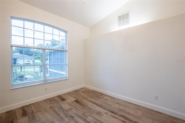 spare room featuring lofted ceiling and hardwood / wood-style flooring