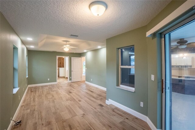 empty room featuring ceiling fan, a textured ceiling, and light hardwood / wood-style flooring