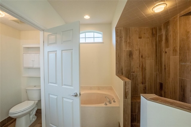 bathroom with a tub to relax in and toilet