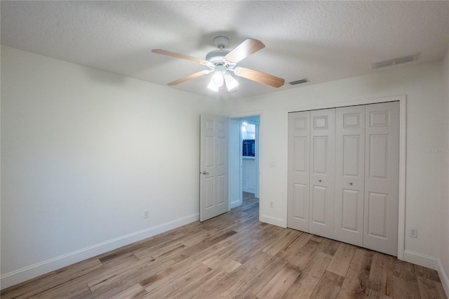 unfurnished bedroom featuring a closet, ceiling fan, light hardwood / wood-style floors, and a textured ceiling