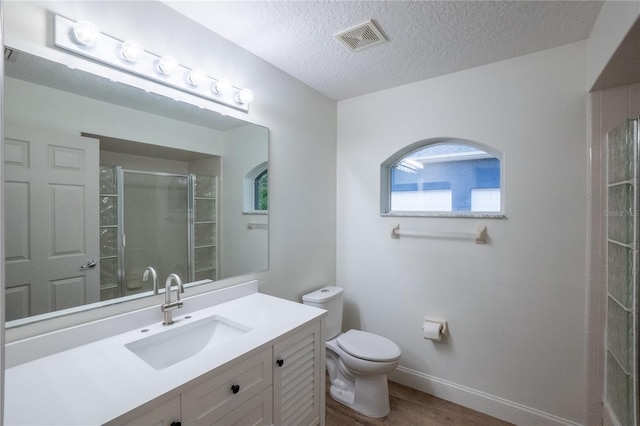 bathroom featuring a textured ceiling, vanity, a shower with shower door, wood-type flooring, and toilet