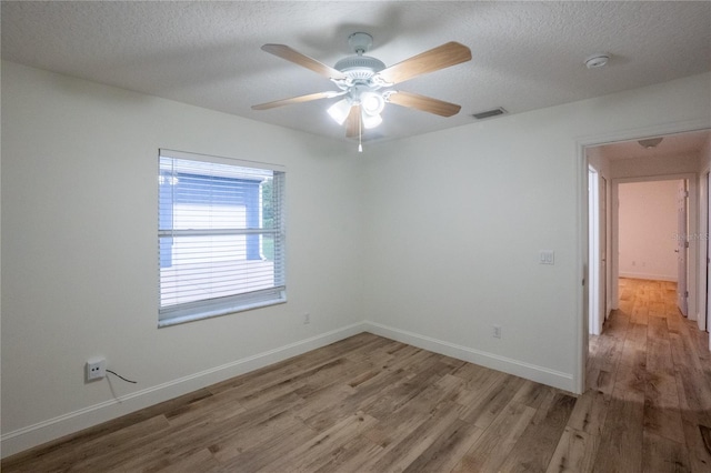 spare room with a textured ceiling, light hardwood / wood-style flooring, and ceiling fan