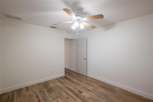 spare room with light wood-type flooring, ceiling fan, and a textured ceiling