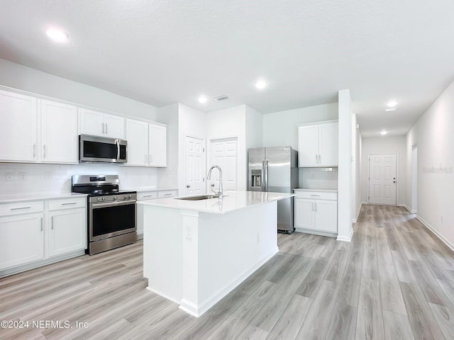 kitchen with sink, light wood-type flooring, an island with sink, white cabinetry, and stainless steel appliances