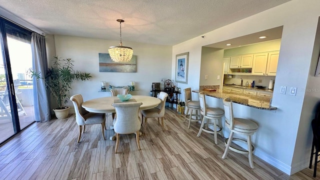 dining area with a textured ceiling, light hardwood / wood-style flooring, a chandelier, and sink