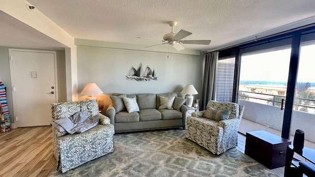 living room featuring ceiling fan, hardwood / wood-style flooring, and a textured ceiling