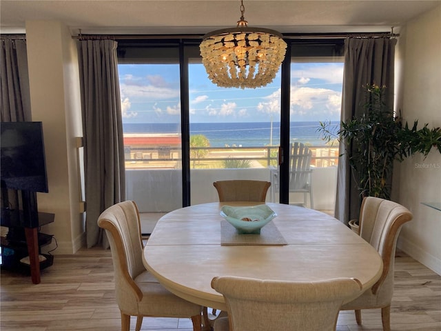 dining room featuring a water view, a chandelier, a beach view, and light hardwood / wood-style flooring