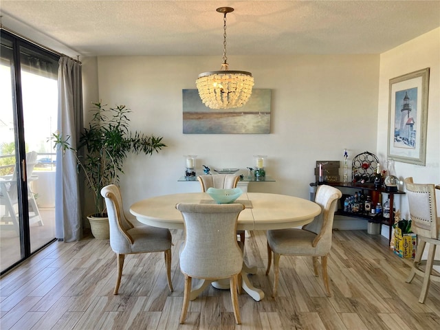 dining room featuring a textured ceiling, light hardwood / wood-style flooring, and a notable chandelier