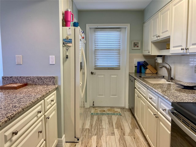 kitchen with light hardwood / wood-style flooring, appliances with stainless steel finishes, sink, light stone counters, and white cabinets