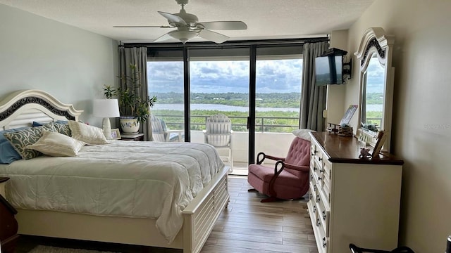 bedroom featuring a textured ceiling, ceiling fan, dark hardwood / wood-style flooring, and access to outside