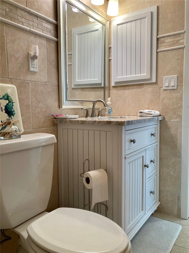 bathroom with tile patterned floors, tile walls, toilet, and vanity