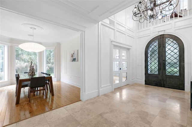 entryway featuring ornamental molding, a chandelier, light hardwood / wood-style floors, and french doors