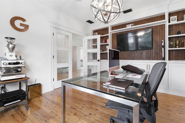 office space with an inviting chandelier, light wood-type flooring, and ornamental molding