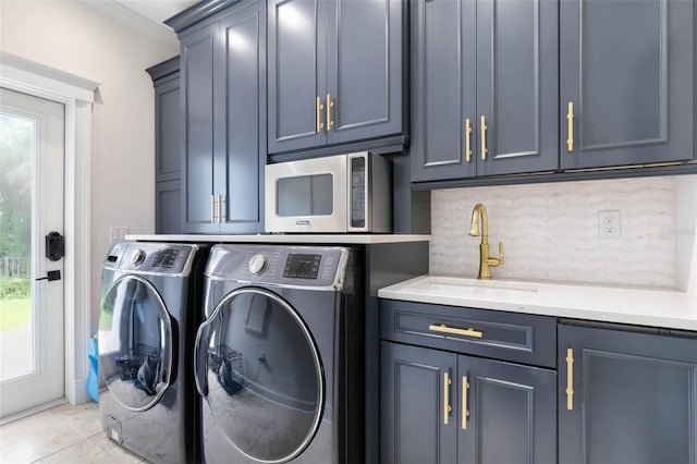 laundry room featuring light tile patterned floors, cabinets, sink, and washing machine and dryer