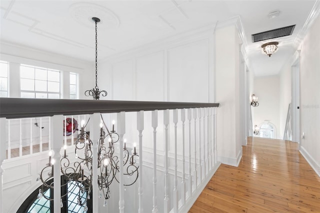 corridor with ornamental molding, a chandelier, and hardwood / wood-style flooring