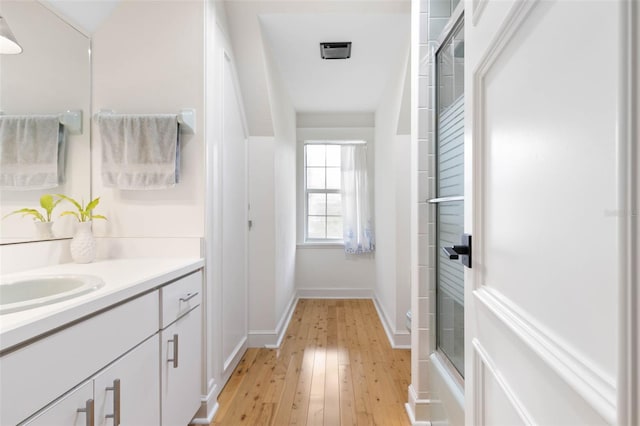 bathroom with wood-type flooring, vanity, and bath / shower combo with glass door