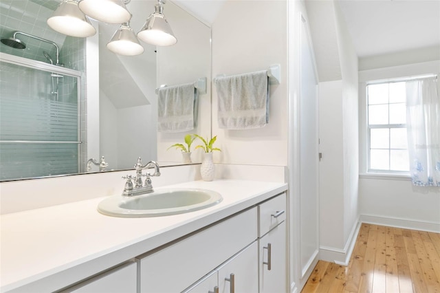 bathroom with wood-type flooring, a shower with door, and vanity